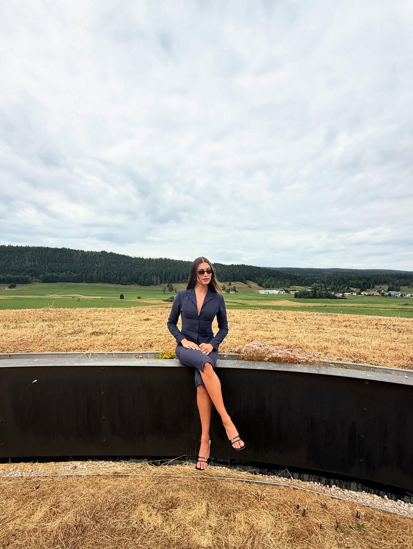 Hailey wears a navy blazer, navy pedal pushers, and black open-toe heeled mules.
