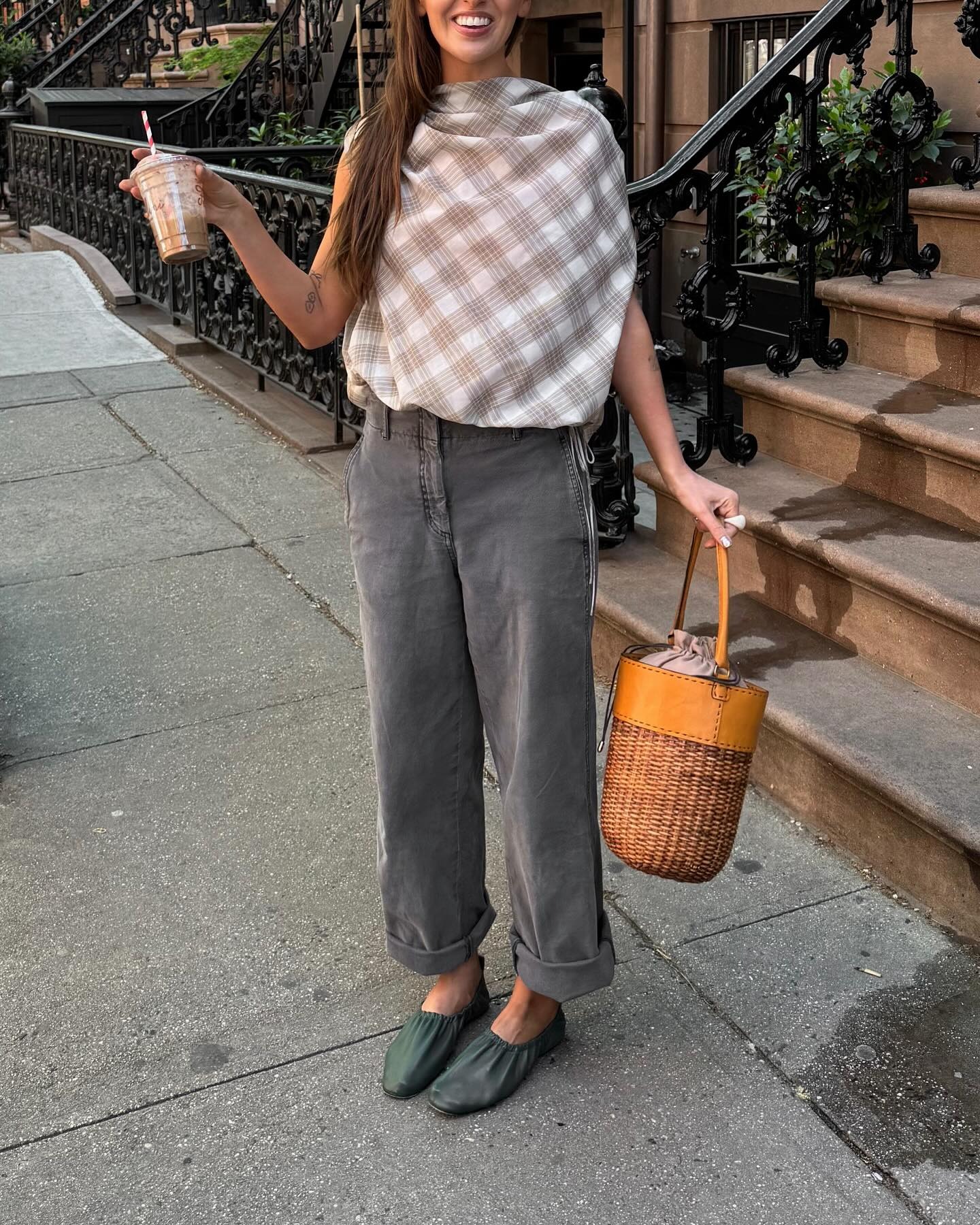 Makenna wears a plaid top, gray jeans, green flats, and a straw bucket bag.