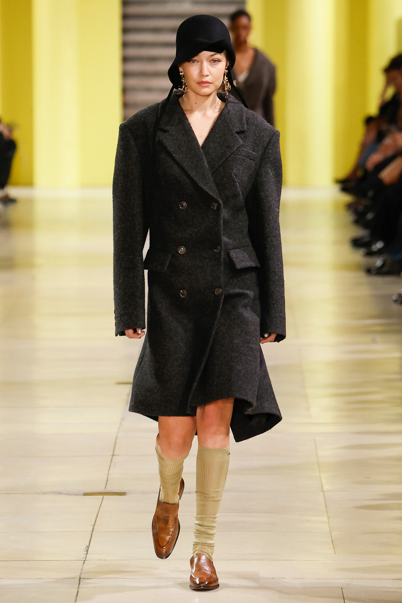 A model wearing a black coat and sheer socks on a Miu Miu runway