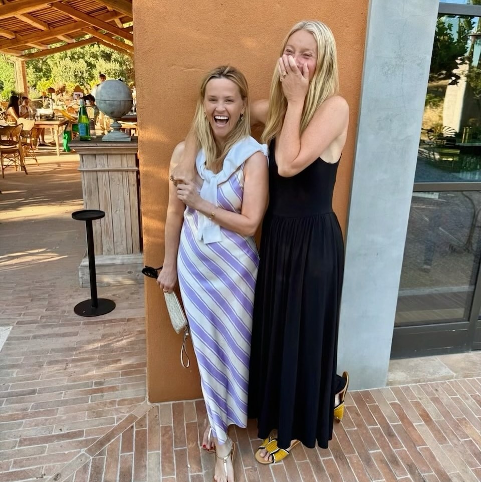 Gwyneth Paltrow wears a black dress and yellow sandals in a picture with Reese Witherspoon