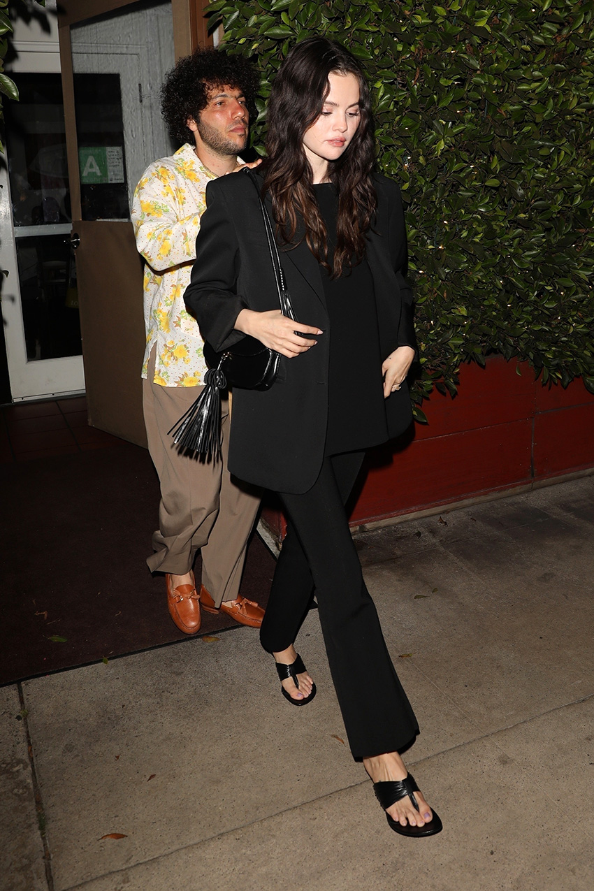 Selena Gomez wearing a black blazer, black cropped pants, and kitten-heel thong sandals with Benny Blanco