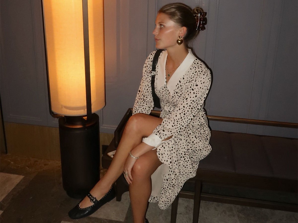 Influencer Laure Elson wears a polka dot dress and Reformation flats. She swears Blinker and Eliza heart earrings.