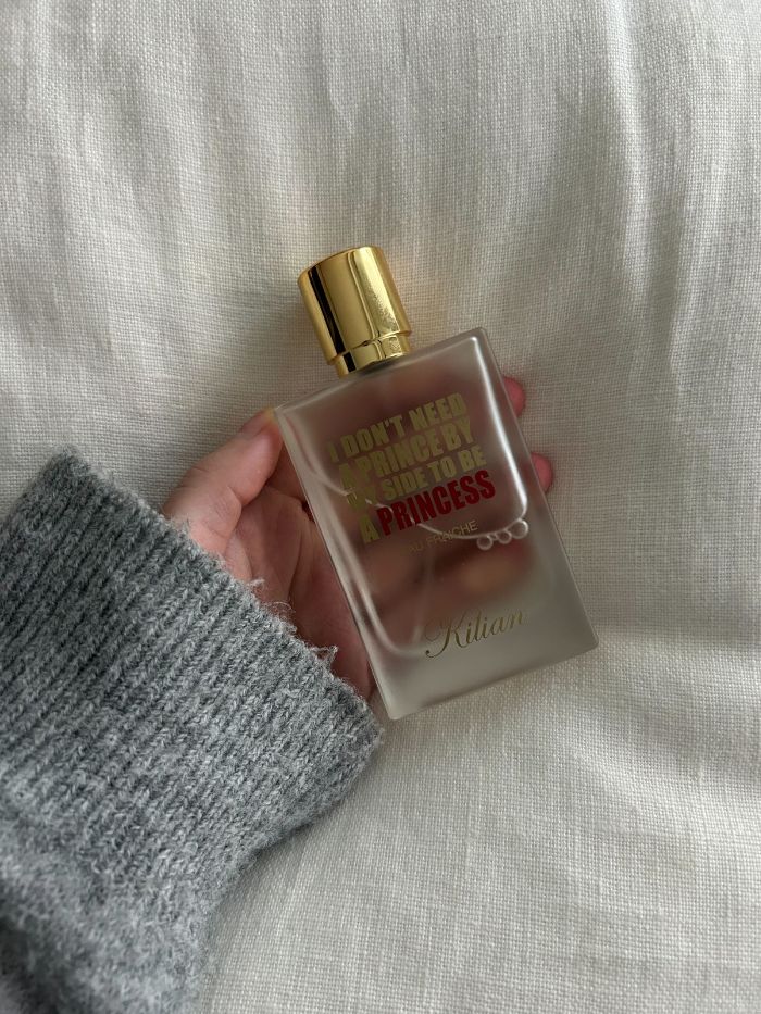 Junior beauty editor holding the Kilian Paris Princess Eau Fraiche perfume on a white linen background