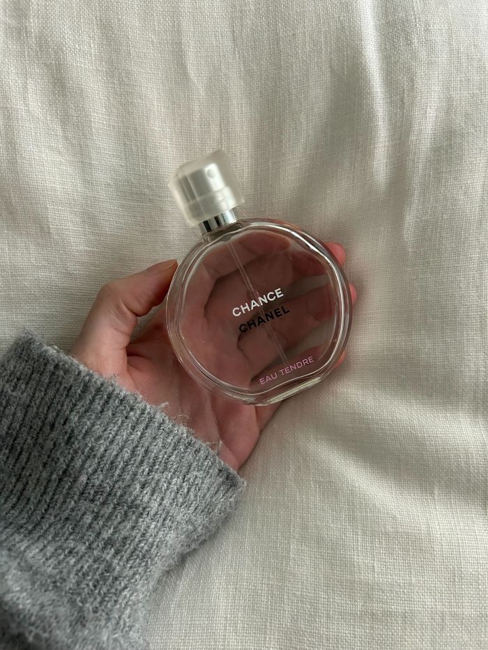 Junior beauty editor holding the Chanel Chance Eau Tendre perfume on a white linen background