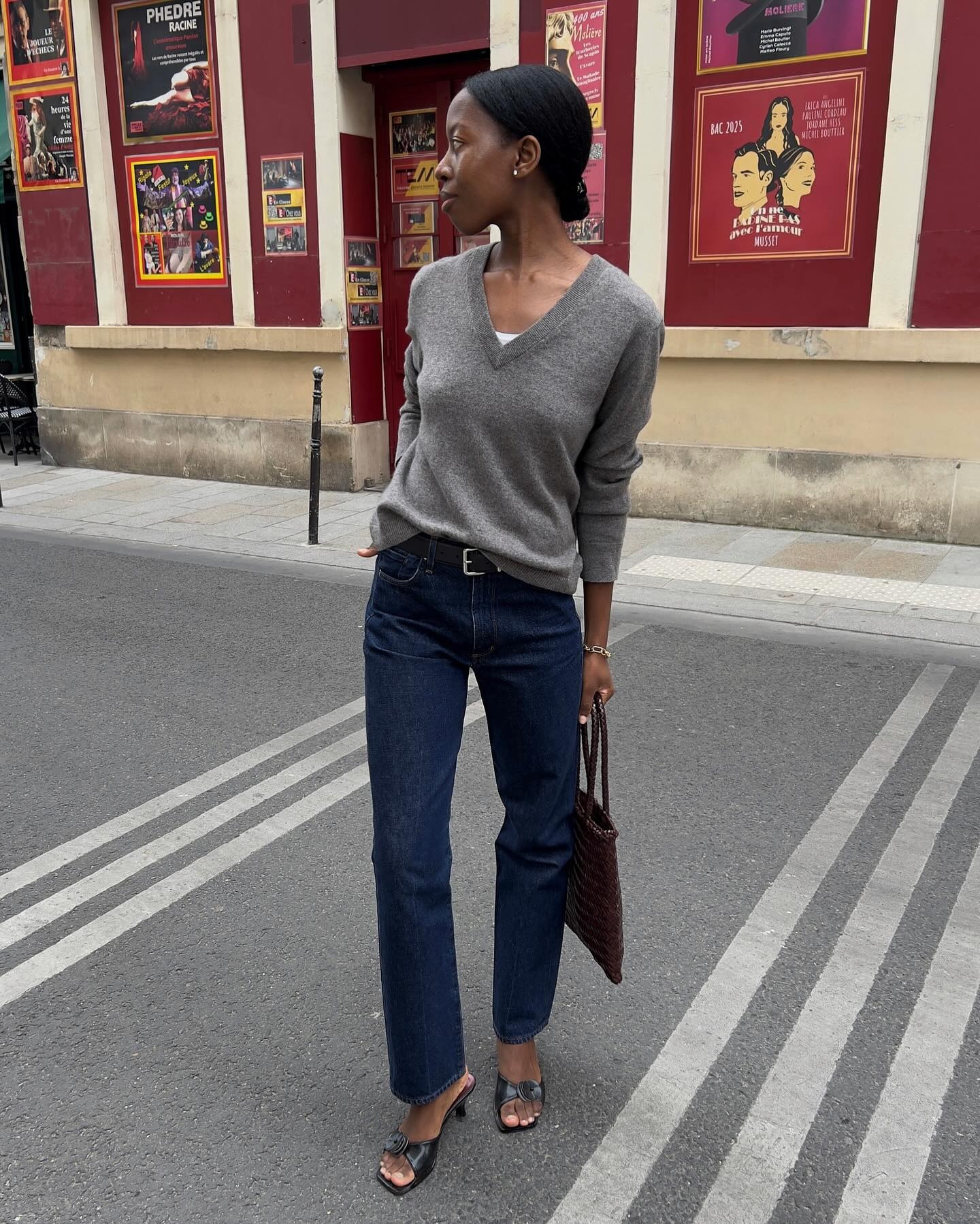 Influencer Sylvie wears dark wash denim with black kitten heels and a white tank. She also wears a grey sweater.