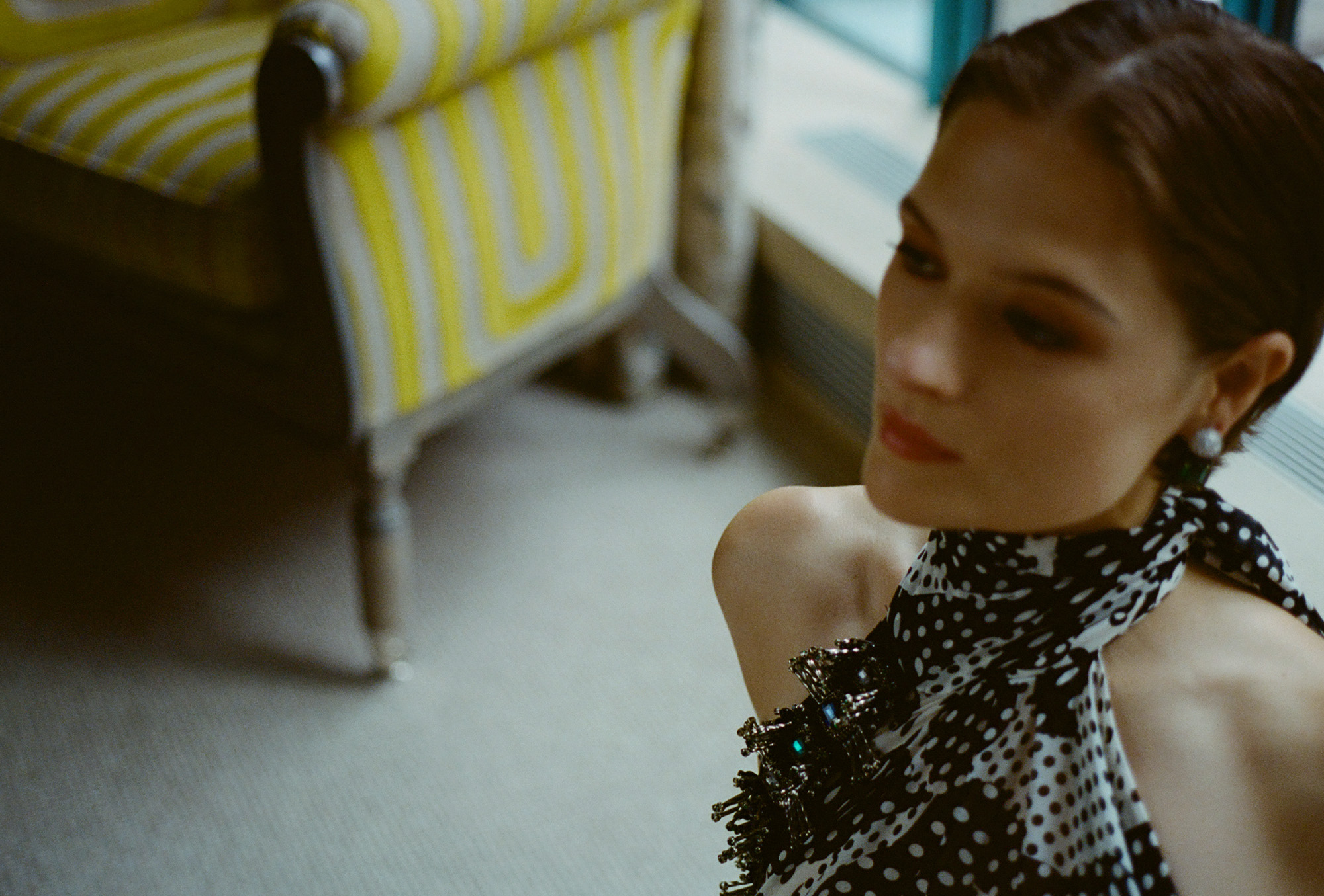 Actress Louisa Jacobson wears a scarf-print Dries Van Noten halter dress with Sauer jewels. She is posing for portraits inside her hotel room before The Gilded Age season 3 premiere.