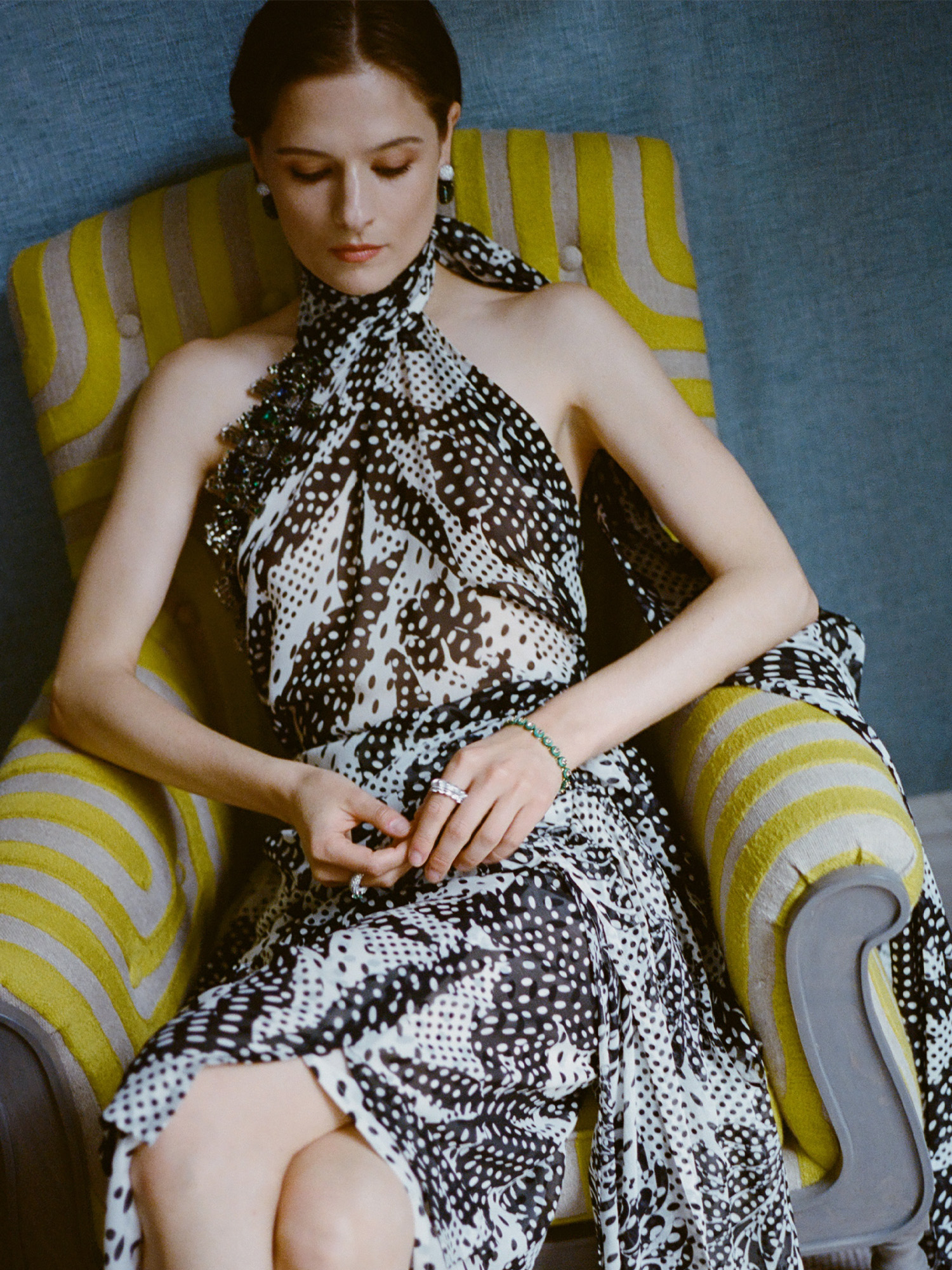 Actress Louisa Jacobson wears a scarf-print Dries Van Noten halter dress with Sauer jewels. She is posing for portraits inside her hotel room before The Gilded Age season 3 premiere.
