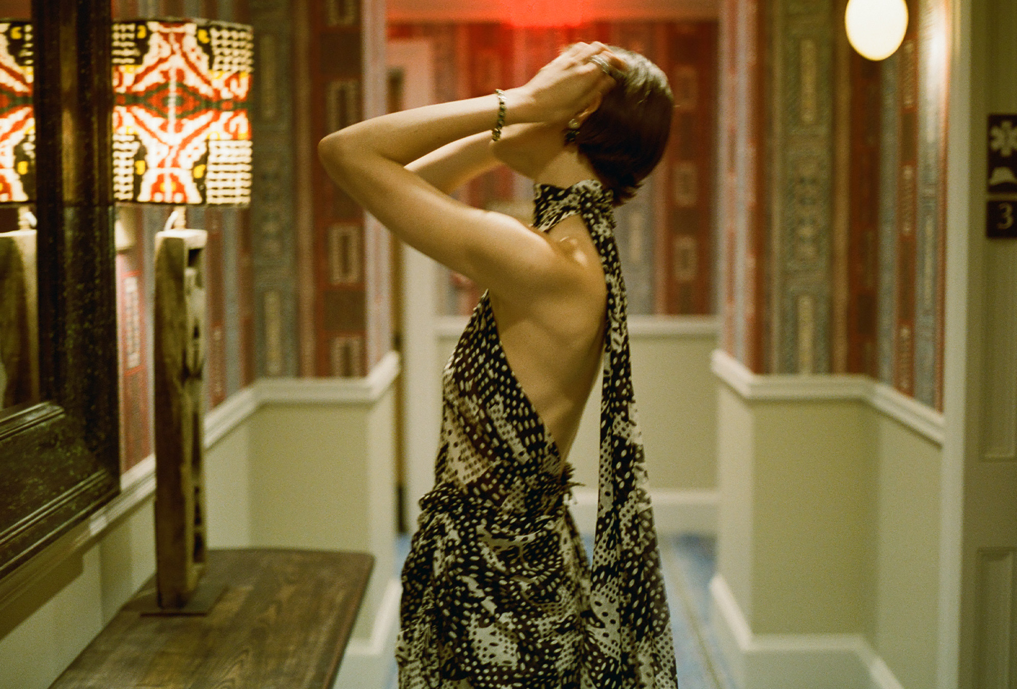 Actress Louisa Jacobson wears a scarf-print Dries Van Noten halter dress with Sauer jewels. She is posing for portraits inside her hotel room before The Gilded Age season 3 premiere.