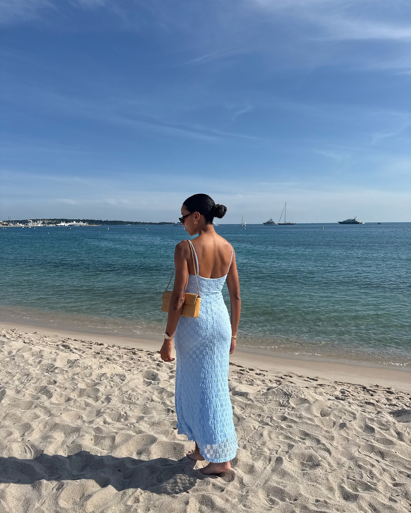 Influencer @amaka.hamelijnck wears a blue bikini with a yellow sarong on the beach.