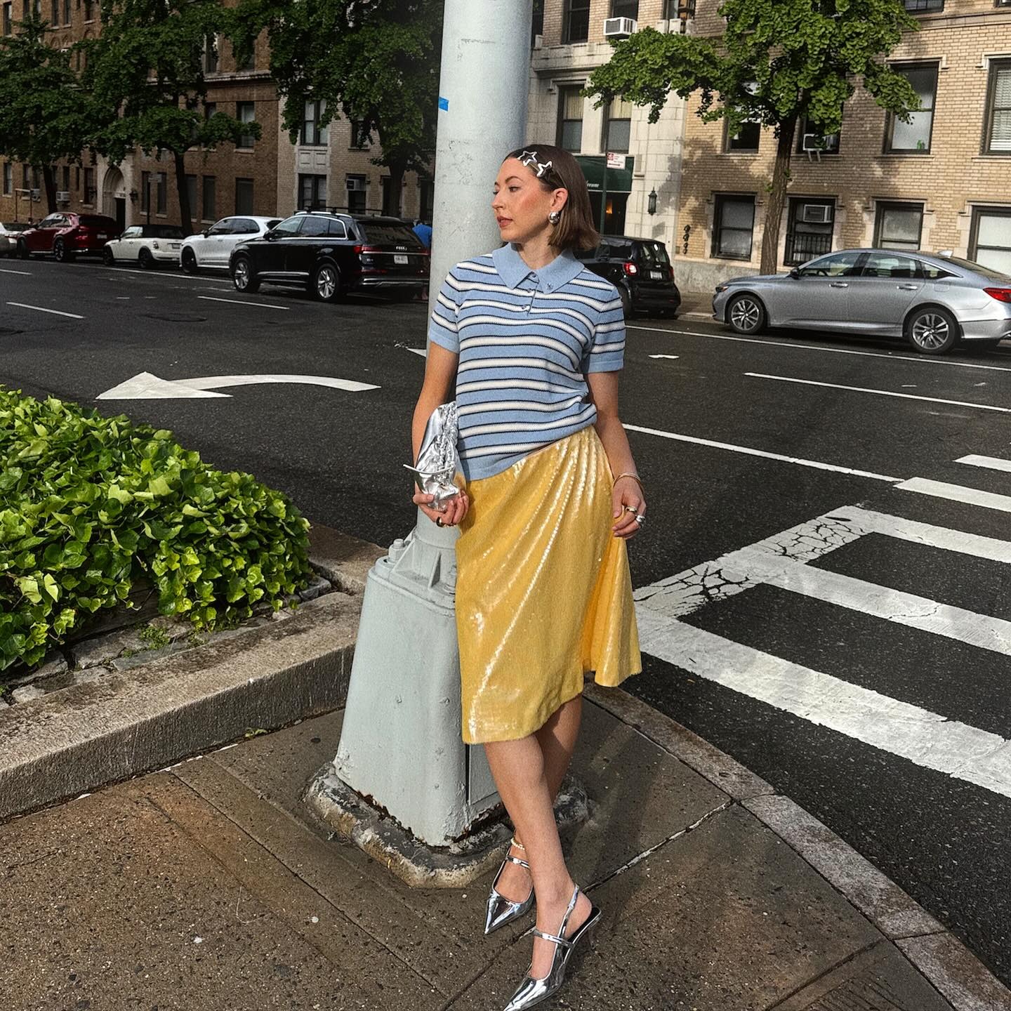 Influencer wears a baby blue knit with a yellow skirt and metallic silver heels.