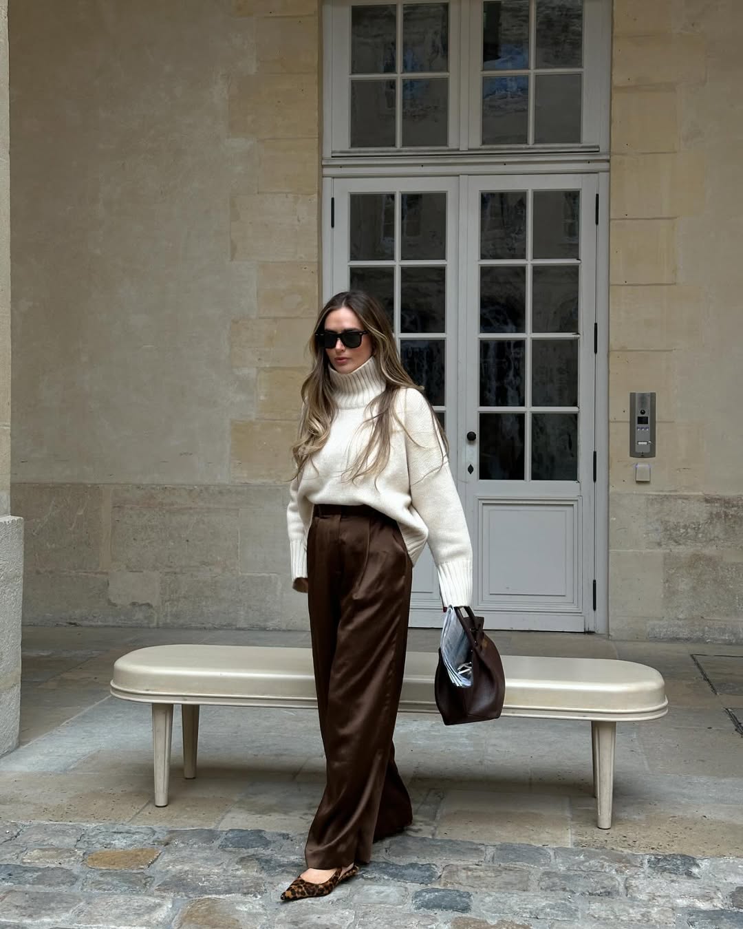 Olivi Faeh wearing brown silk pants with a cream turtleneck sweater