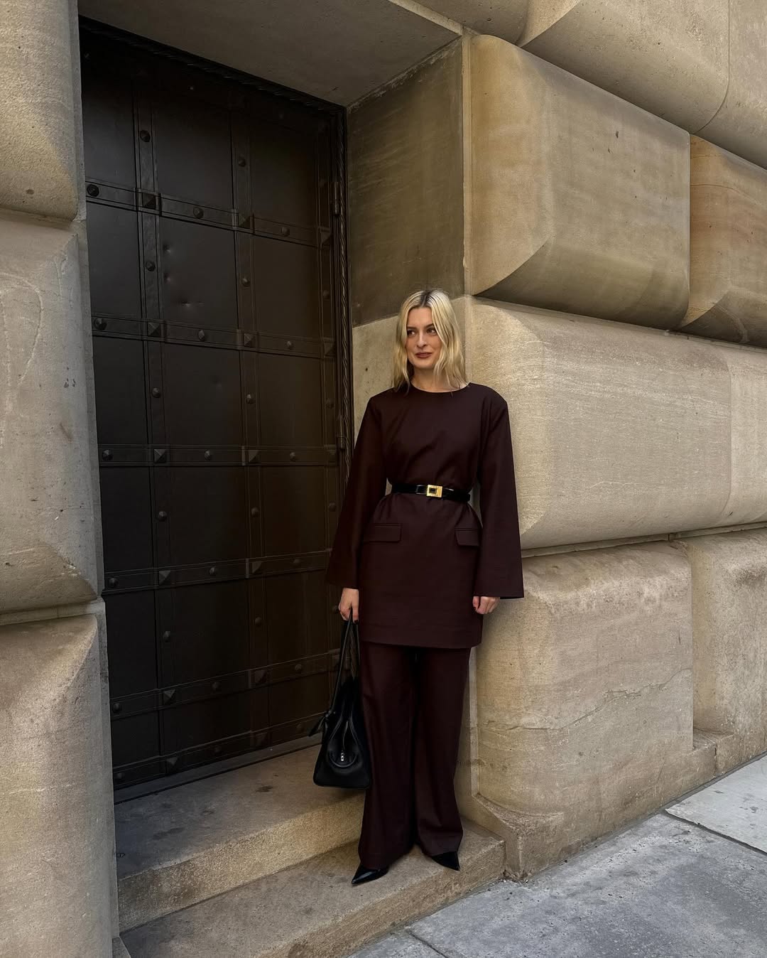 Christie Tyler wearing a brown tunic with brown pants and black accessories