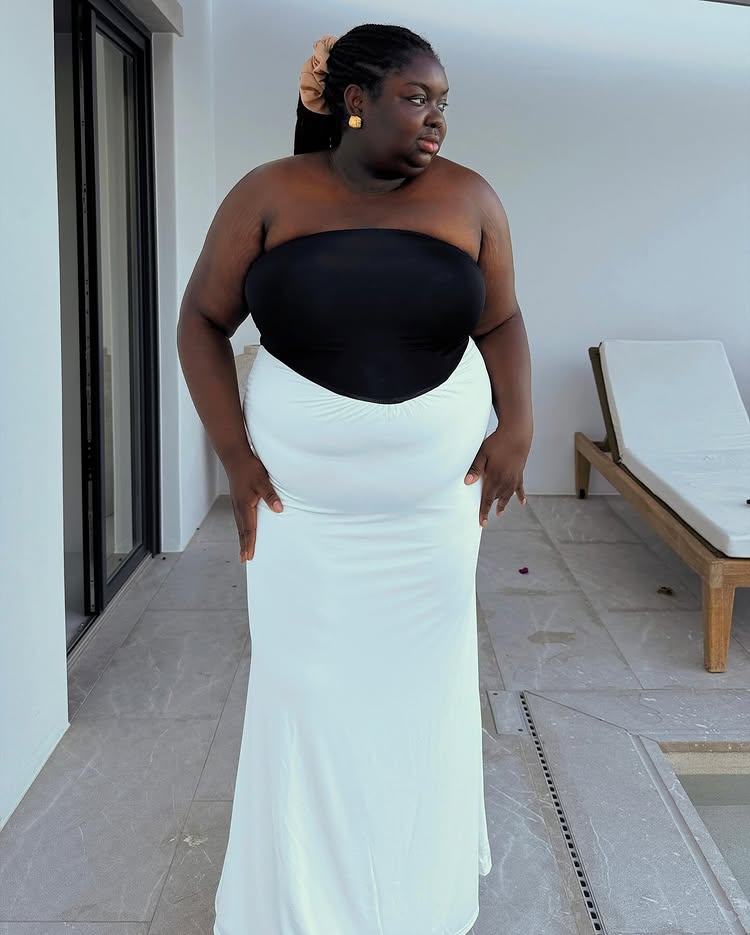 @abimarvel wears a black top and white skirt