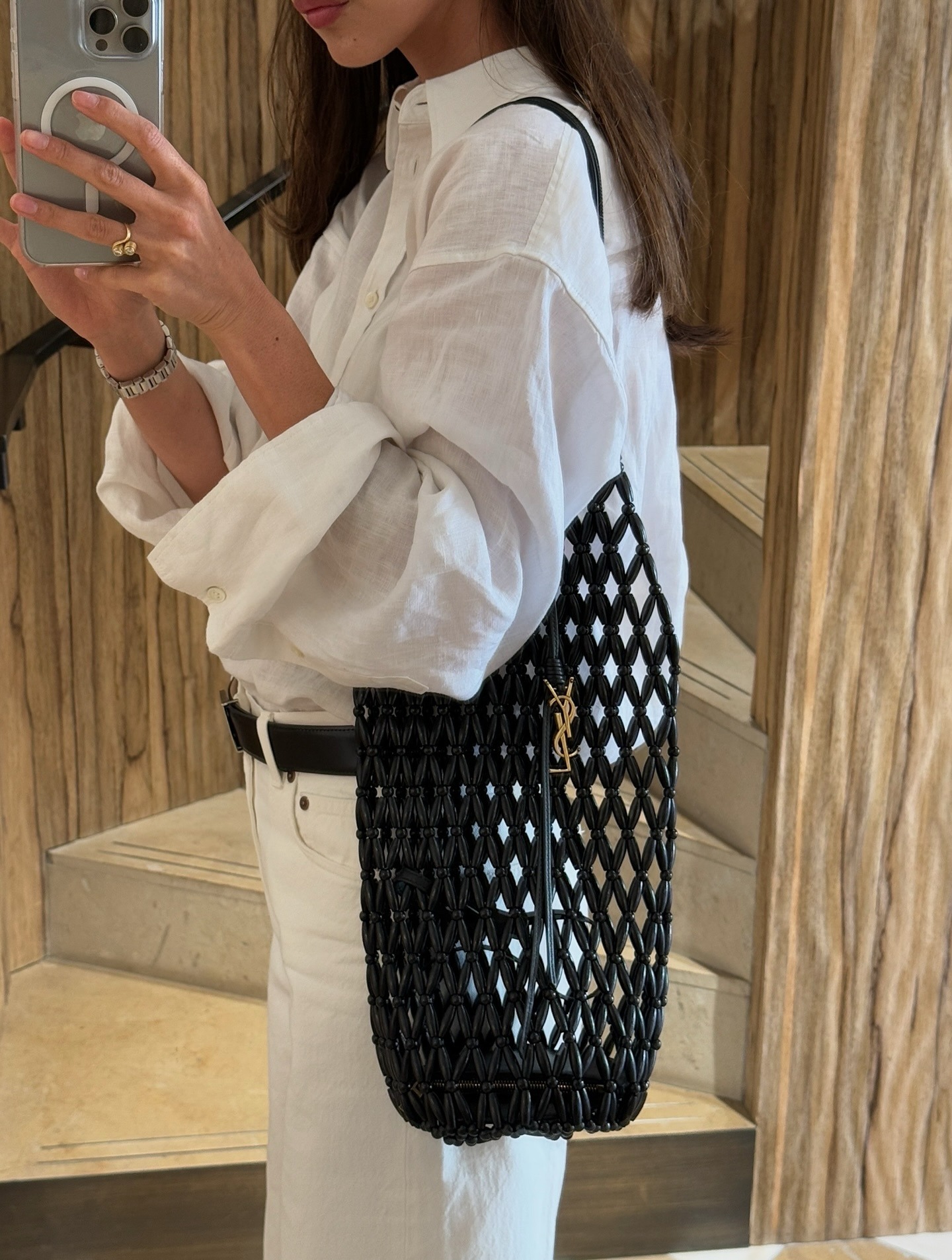 Woman holding a designer beach bag from Saint Laurent.