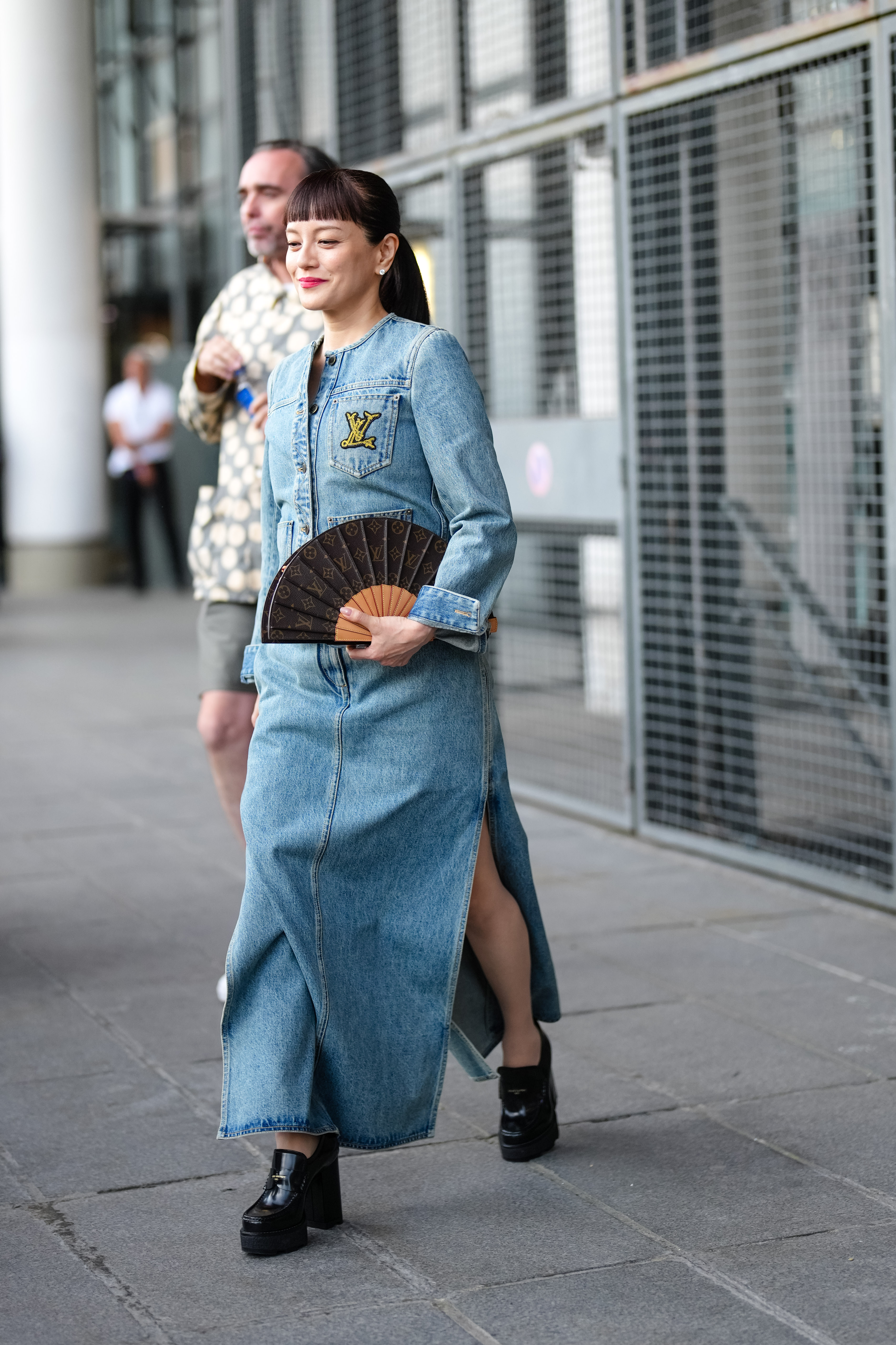 A woman wearing a denim jacket, a denim skirt, and black platform boots