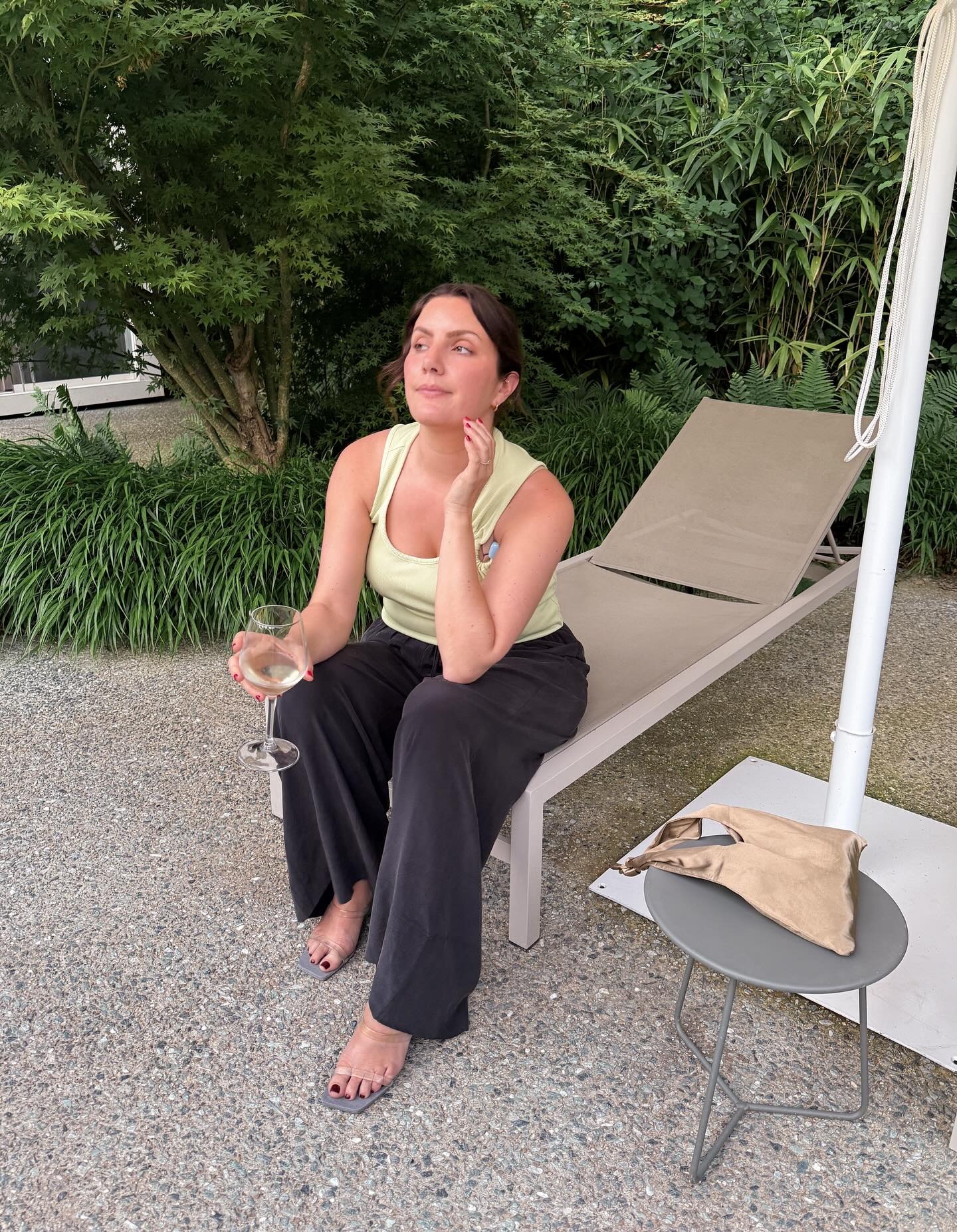 A woman sat on a sunbed wearing sandals with a deep red pedicure