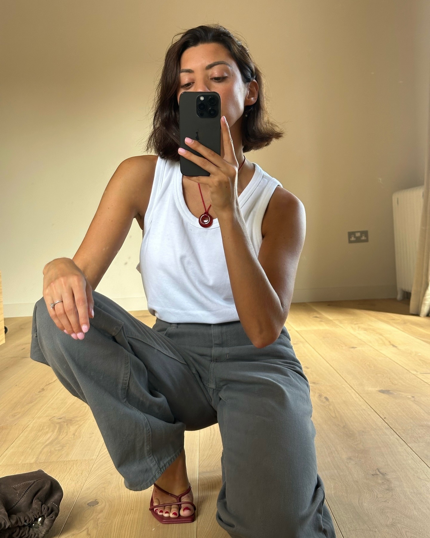 A woman taking a mirror selfie wearing red heels with a deep red pedicure