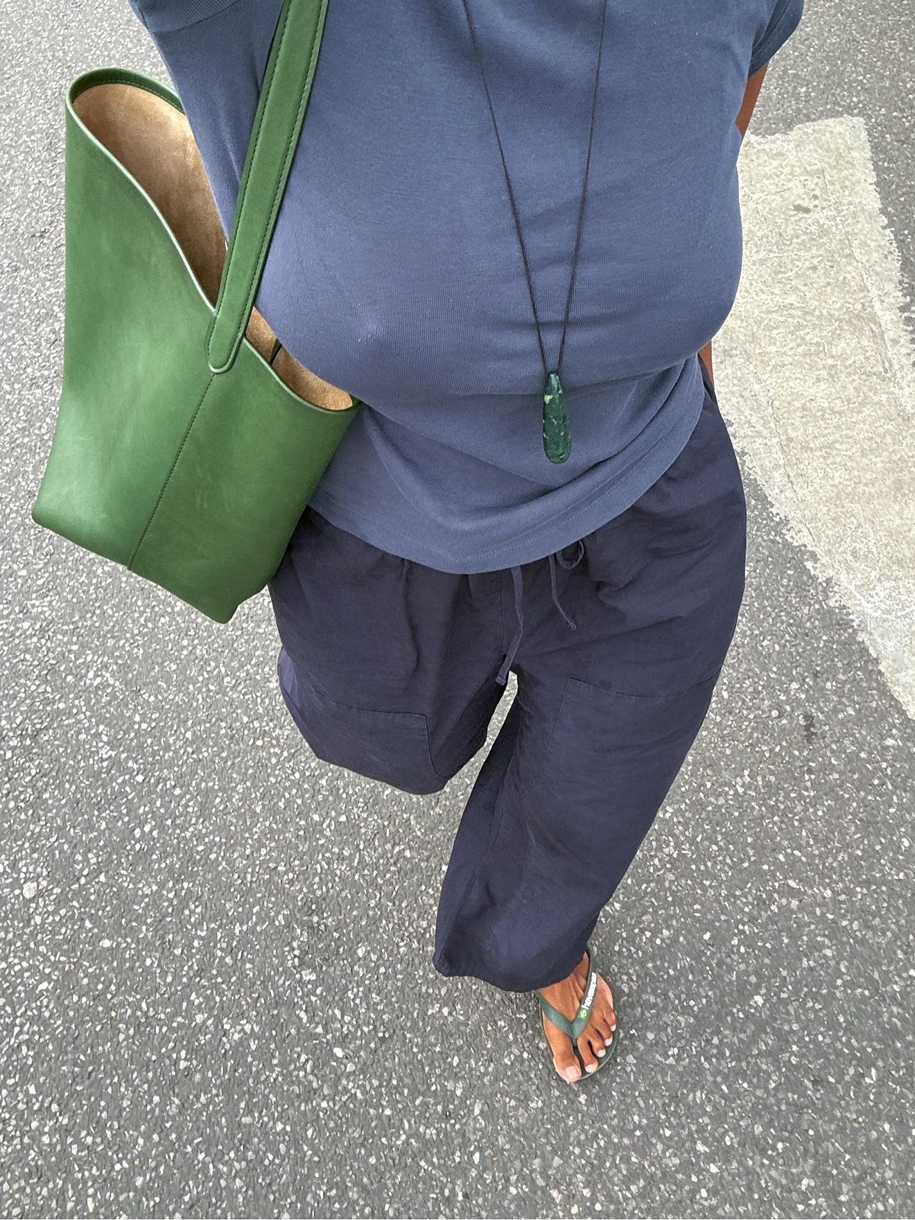 A woman walking wearing green flip flops with a nude pedicure