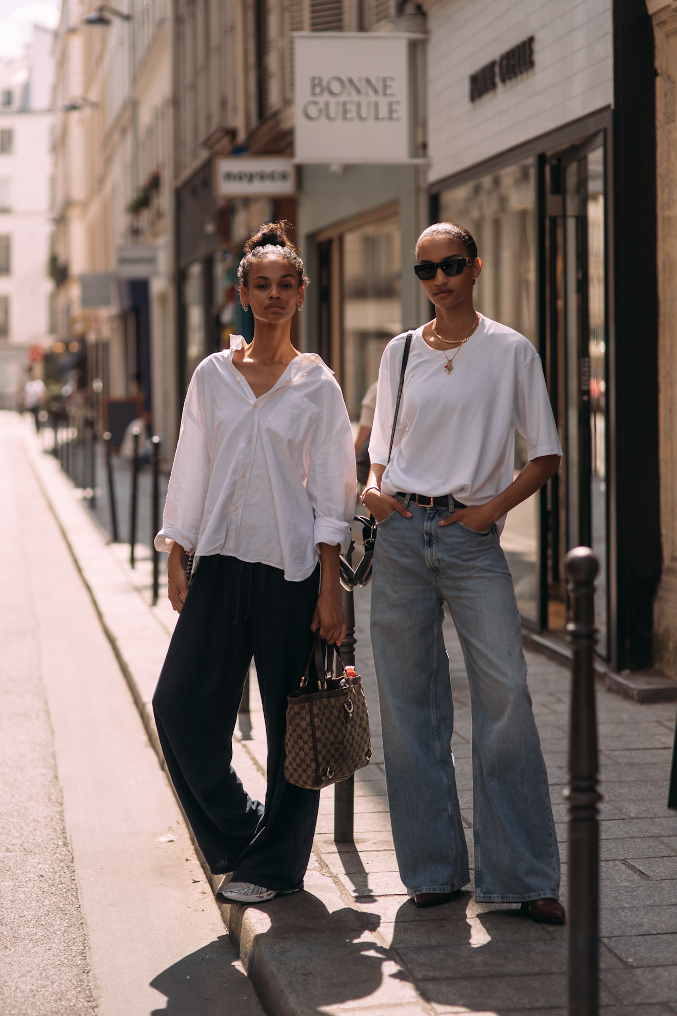 Two models outside of shows wearing white tops with jeans.