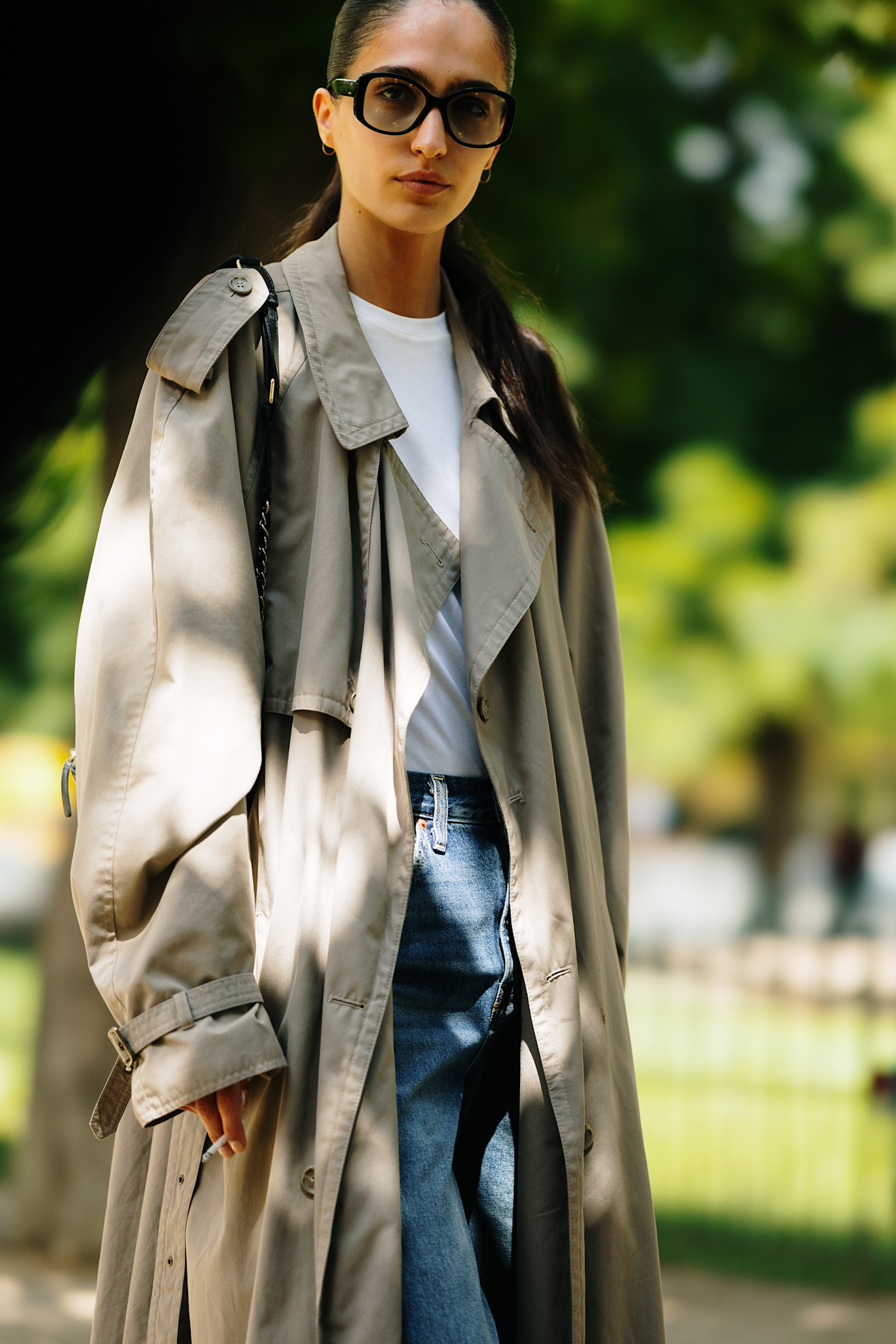 A model outside of Chanel wearing a trench coat, white T-shirt, and jeans.