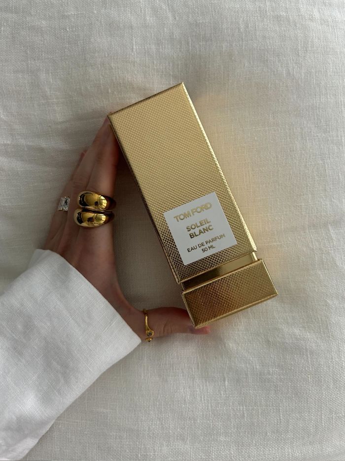 Junior beauty editor Grace Lindsay holding the Tom Ford Soleil Blanc perfume in its gold box