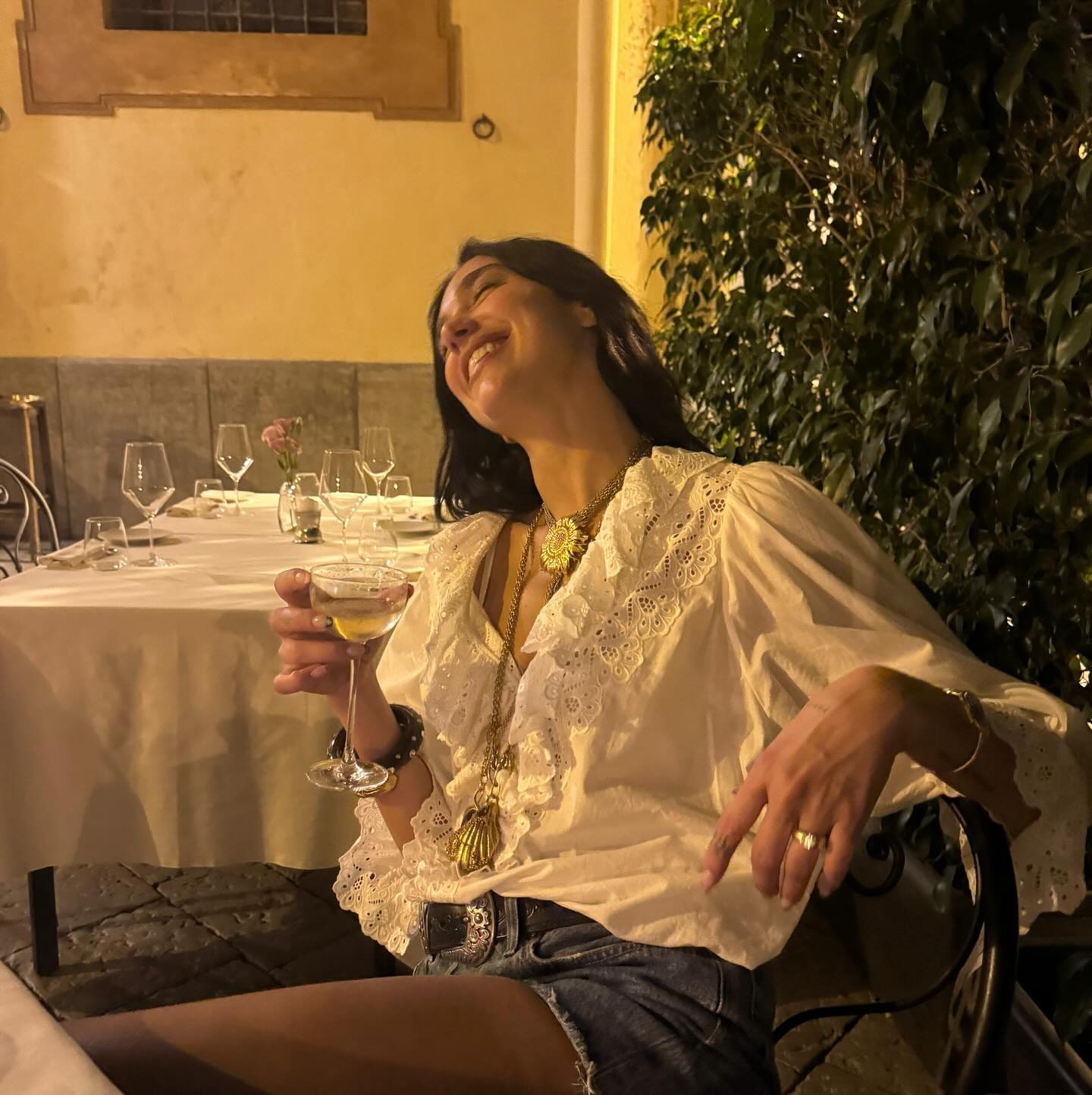 Dua Lipa wearing a pretty white shirt and denim shorts on vacation in Palermo, Italy