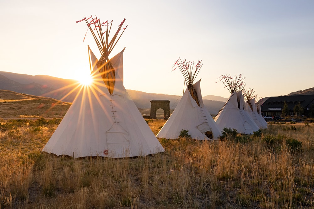 Native Americans teepees in front of a setting sun