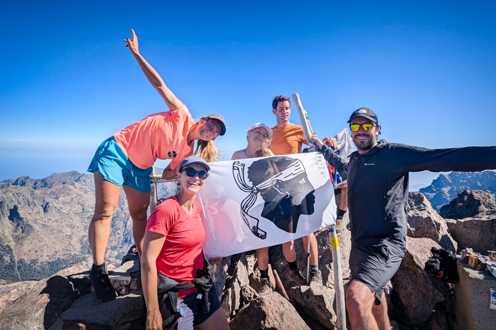 Hikers holding up a Corsican flag on the summit
