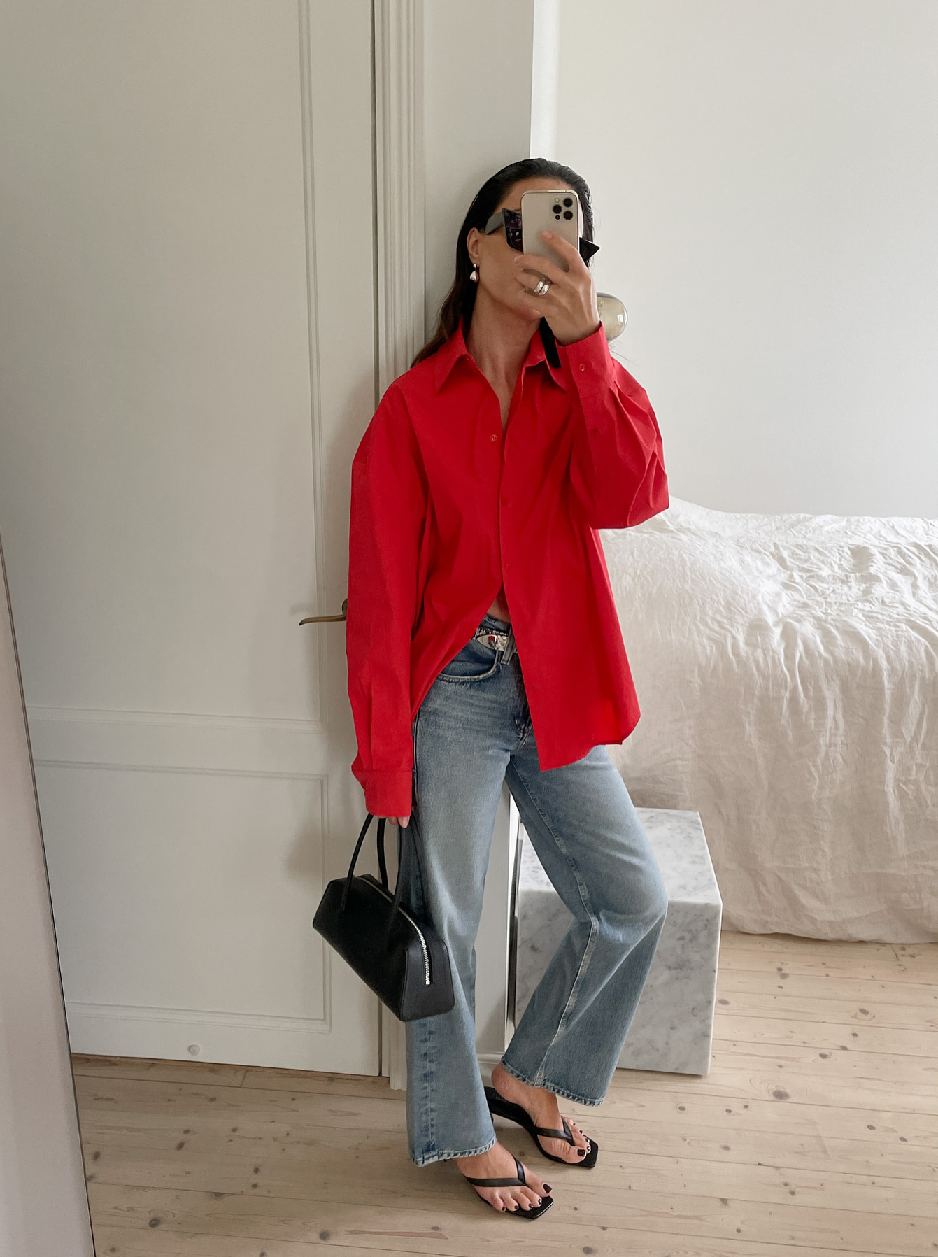 @johannapiispa wears a red shirt with pale blue flared jeans and black heeled sandals