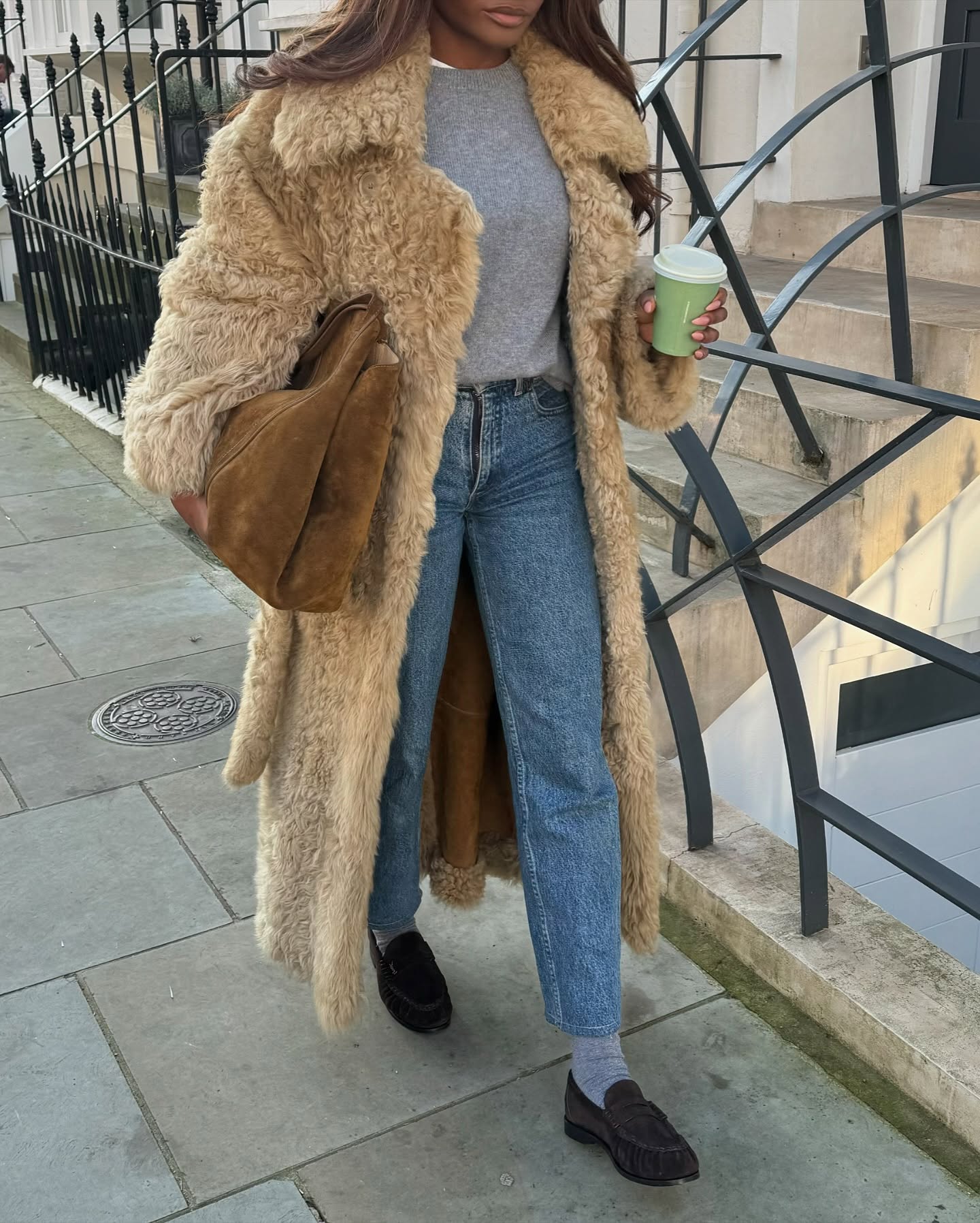 @mimi.orere wears a faux fur coat, blue jeans and brown suede loafers