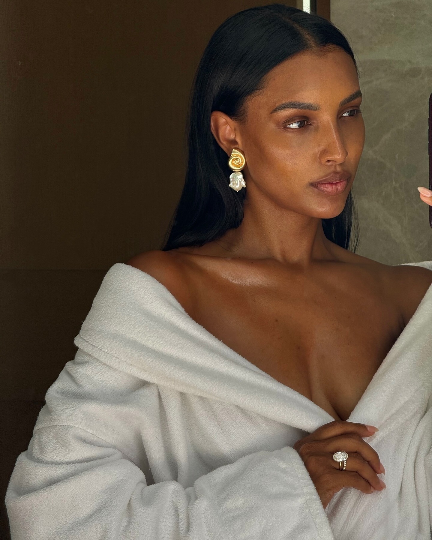Jasmine Tookes taking a selfie in the mirror, wearing a white dressing gown draped over her shoulders