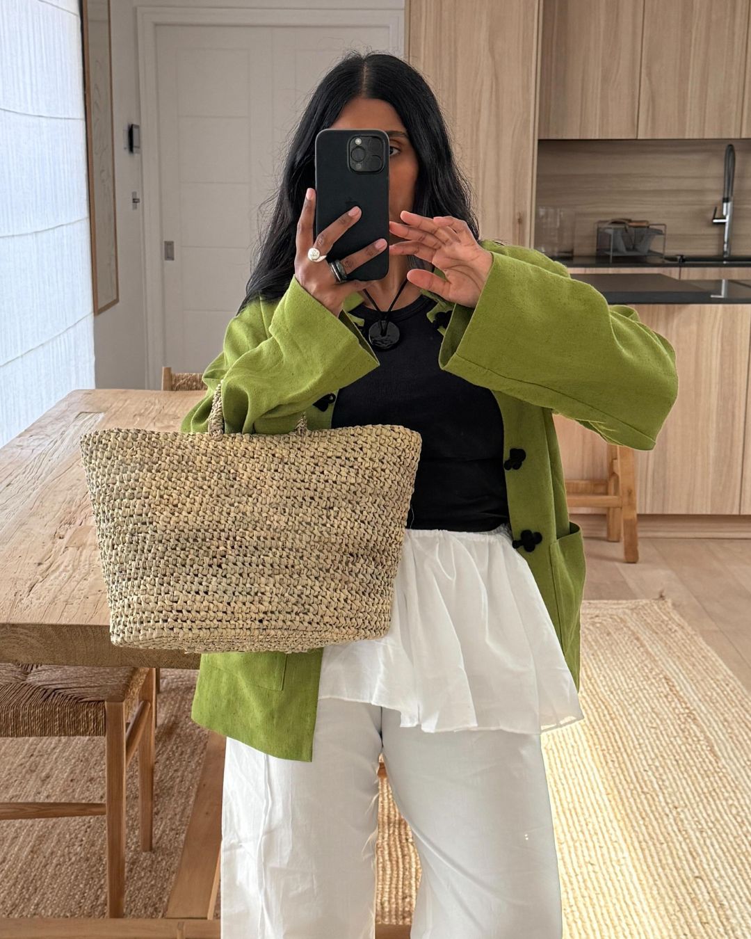 Influencer @monikh wears a dill green jacket with white trousers, a white peplum top and a wicker woven bag.