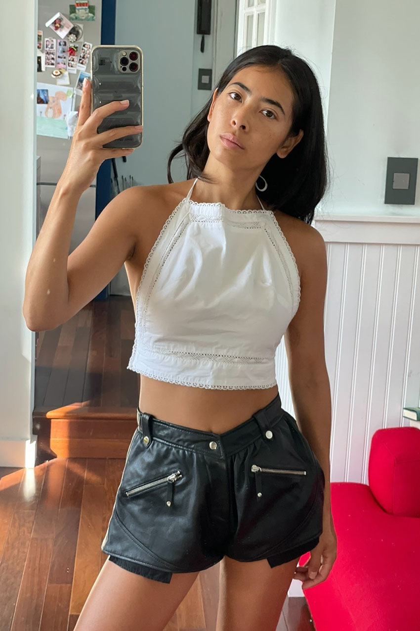 Michelle Li wearing a white lace halter top and black leather shorts with pockets