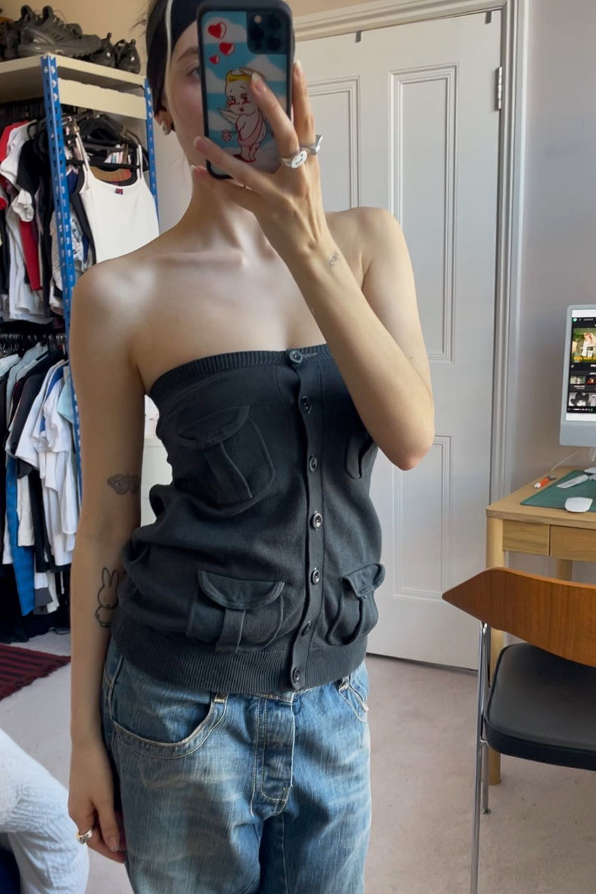 A woman wearing a gray button-down tube top with pockets.