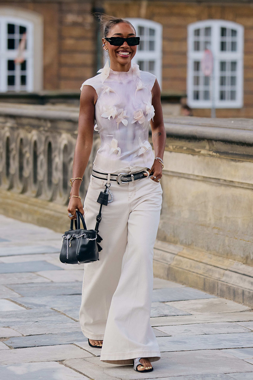 A woman wearing a sheet white textured top and white wide leg jeans with sandals