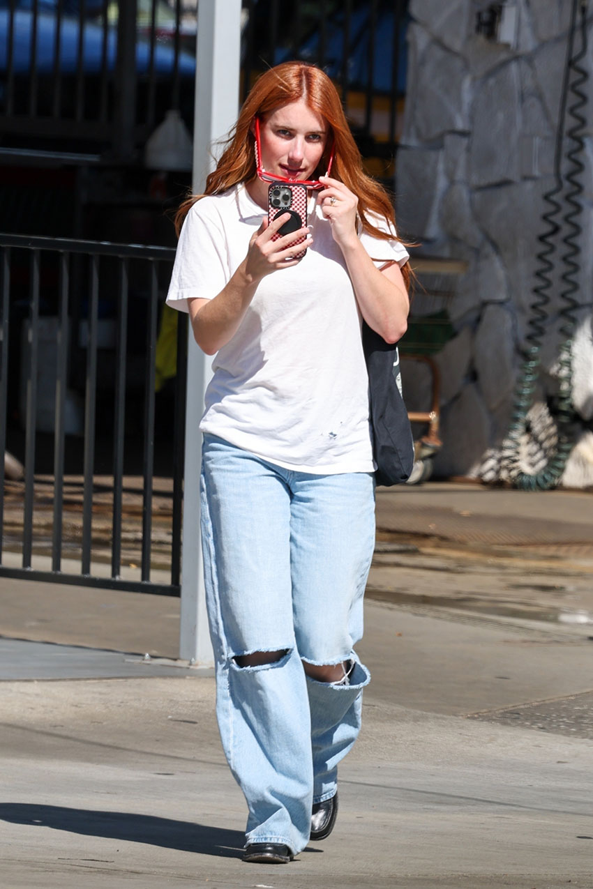 Emma Roberts wearing a plain white T-shirt and ripped, baggy blue jeans.