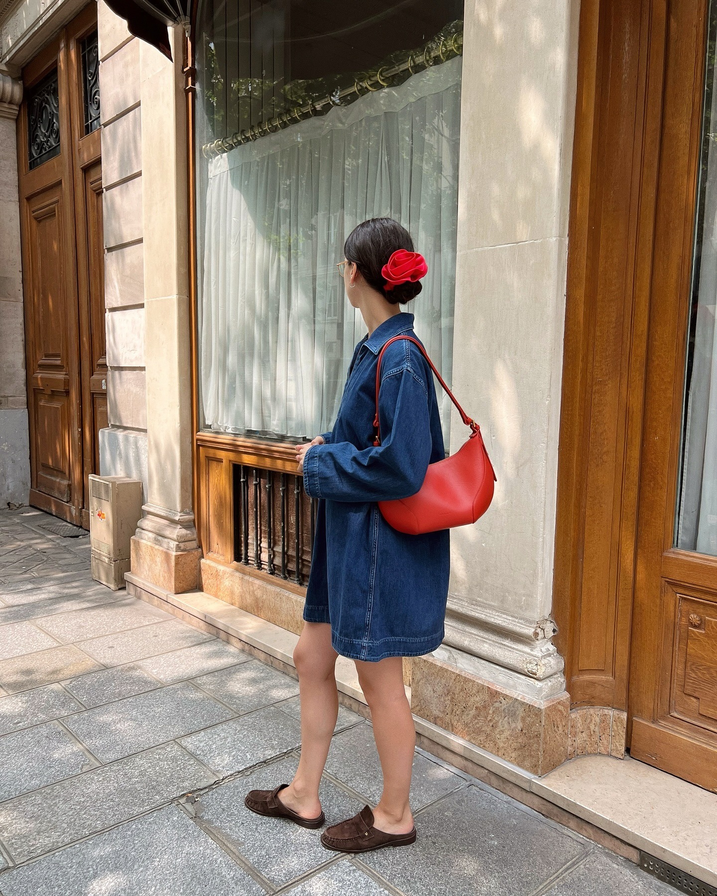 Influencer @pia_mbd wears brown suede mules with a denim minidress and red leather bag.
