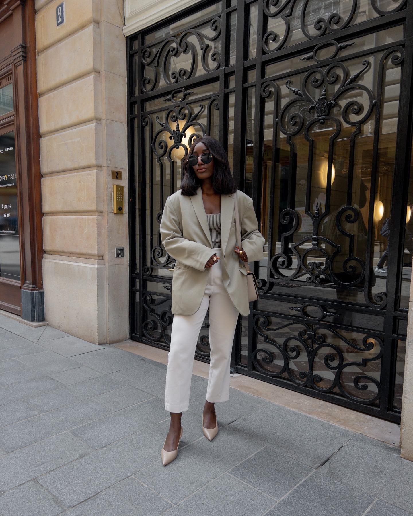 French influencer @aidabadji_ wears a khaki blazer with white cropped trousers.