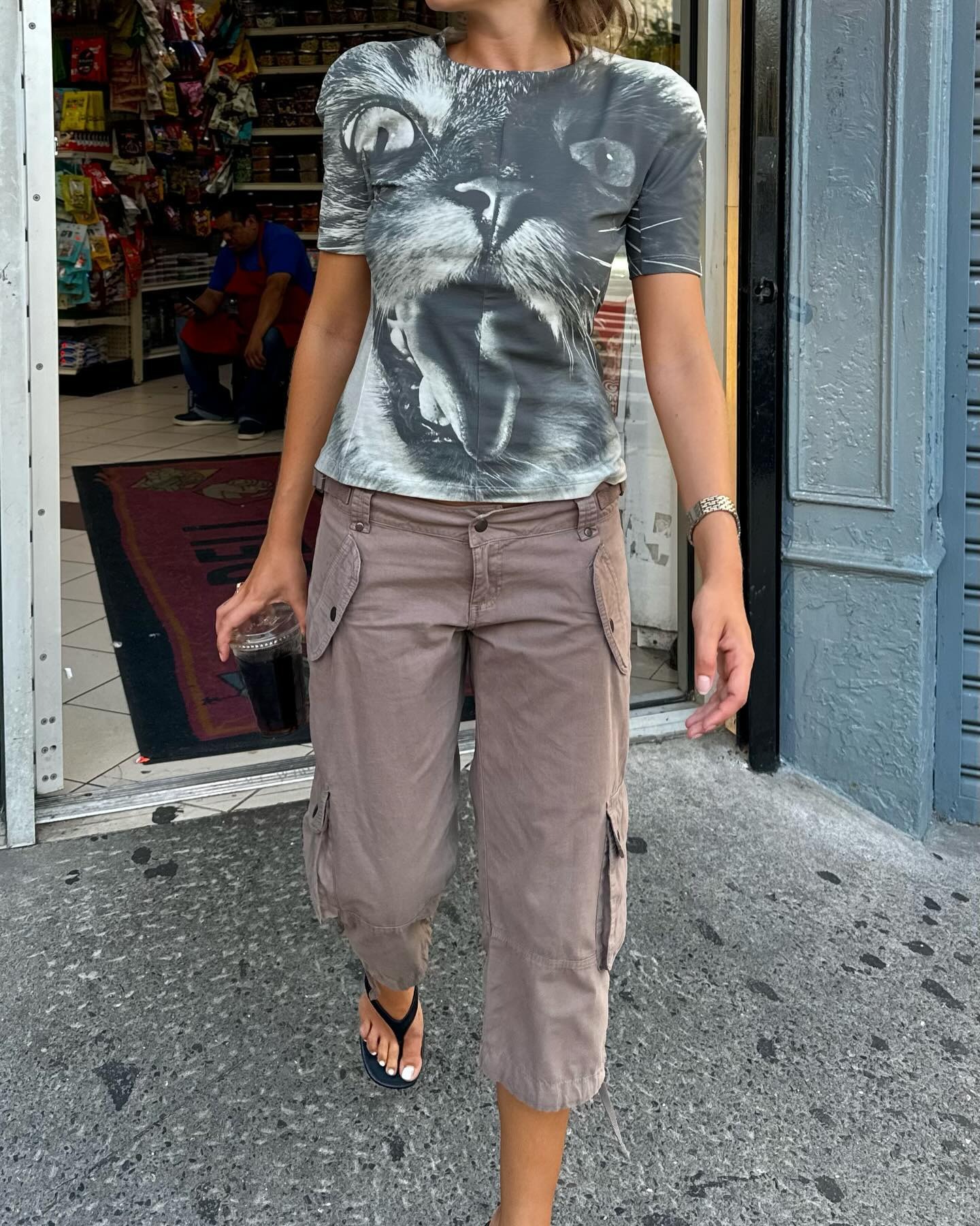 Influencer @rubylyn_ wears long shorts with a grey t-shirt with a cat's face on its front.