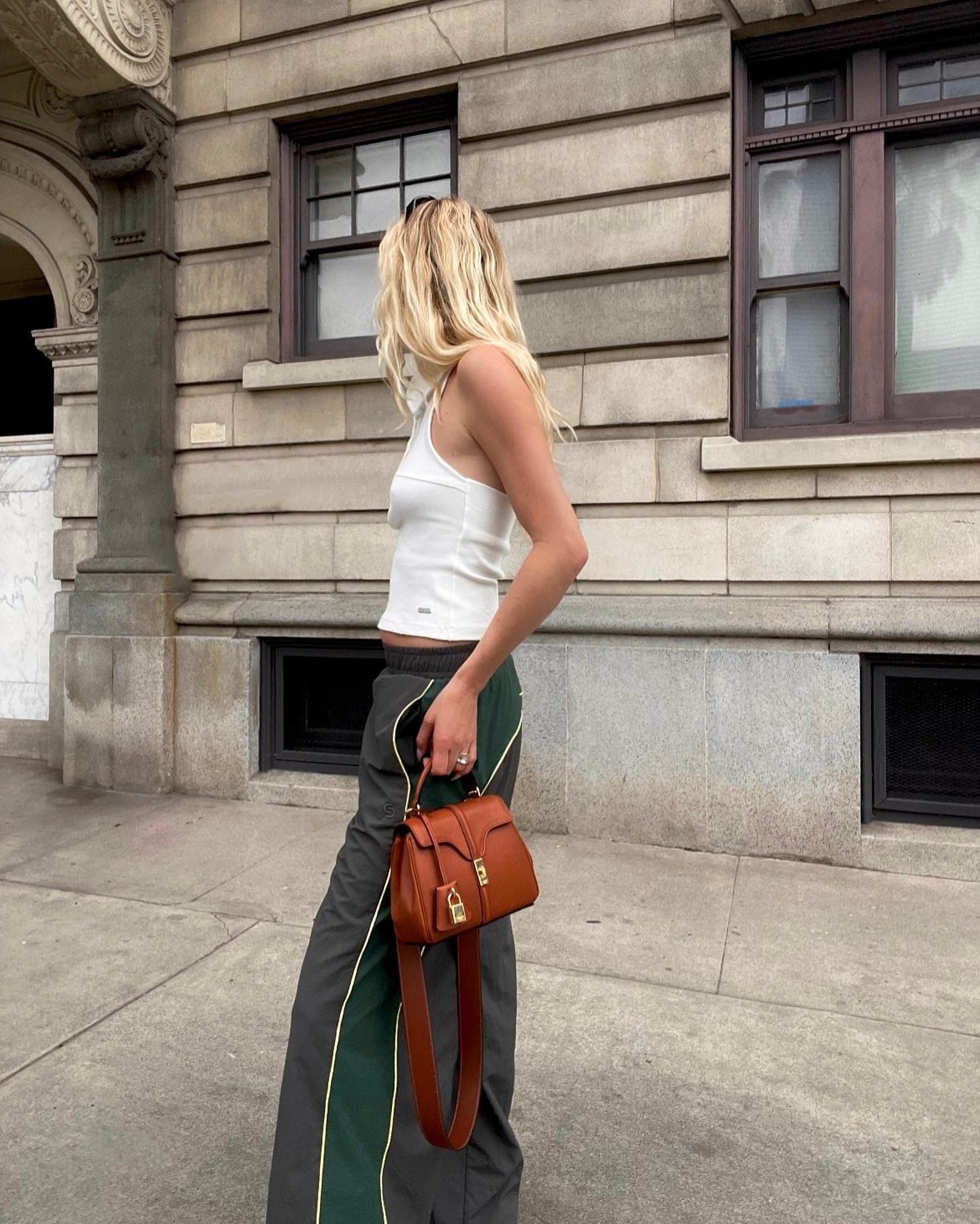 Influencer @meganadelaide wears a white vest top with dark grey track pants.