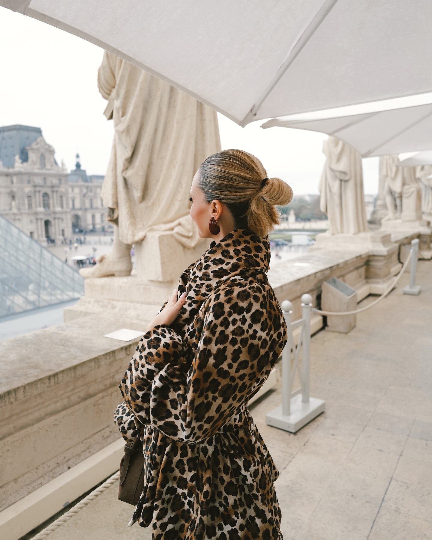 A woman at the Louvre Museum wearing her smudged blonde hair in a bun
