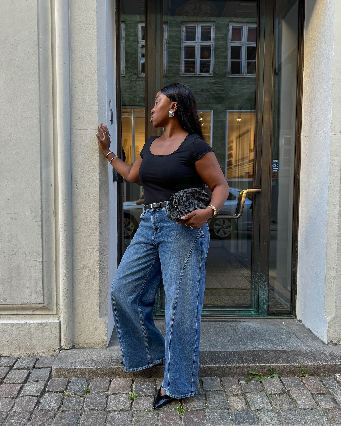 Influencer @nnennaechem stands outside wearing wide-leg jeans and pointed-toe heels.
