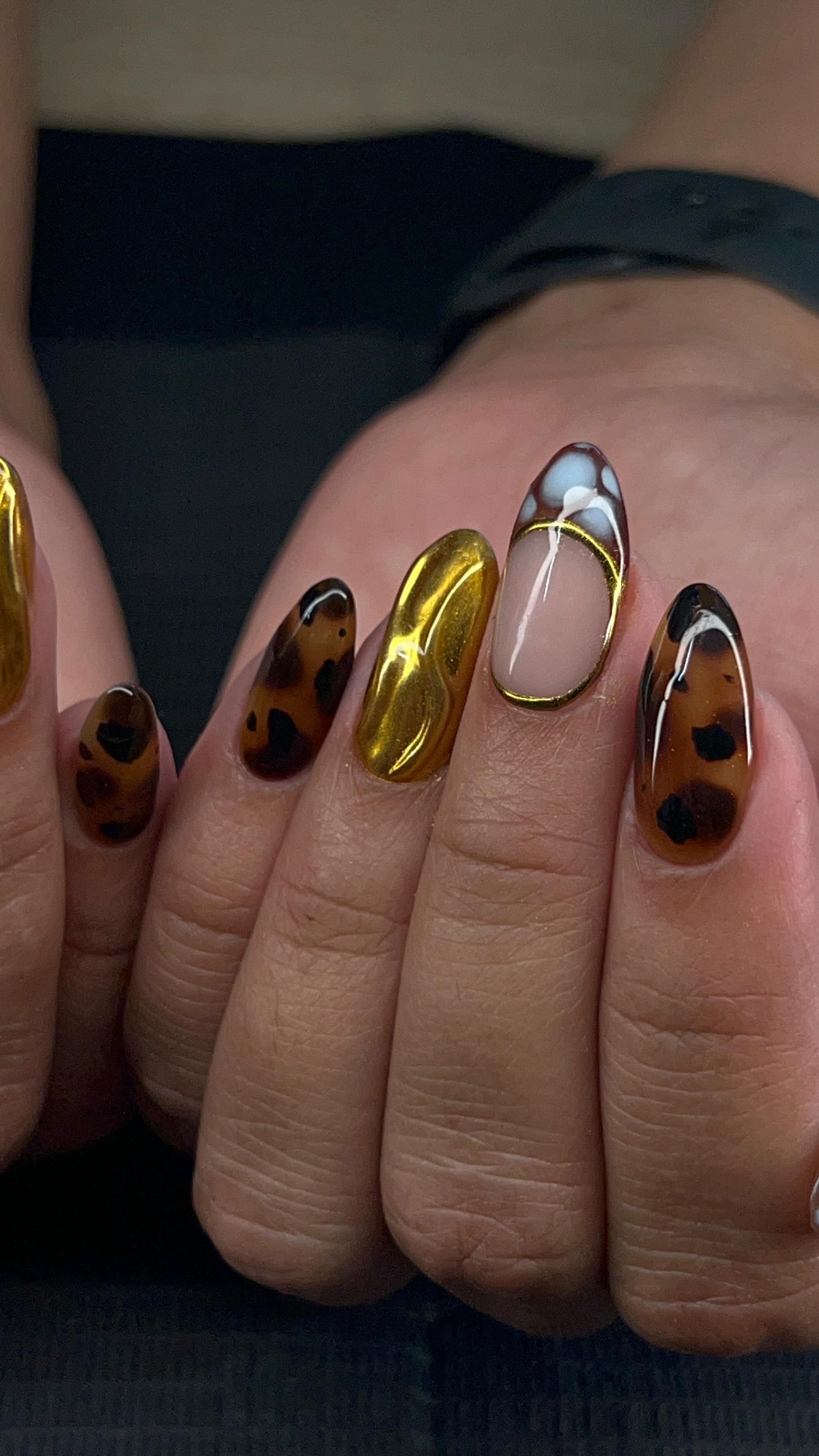 Long almond nails with a mix of nail art designs on each finger, including tortoiseshell, chrome gold and marbled French tips