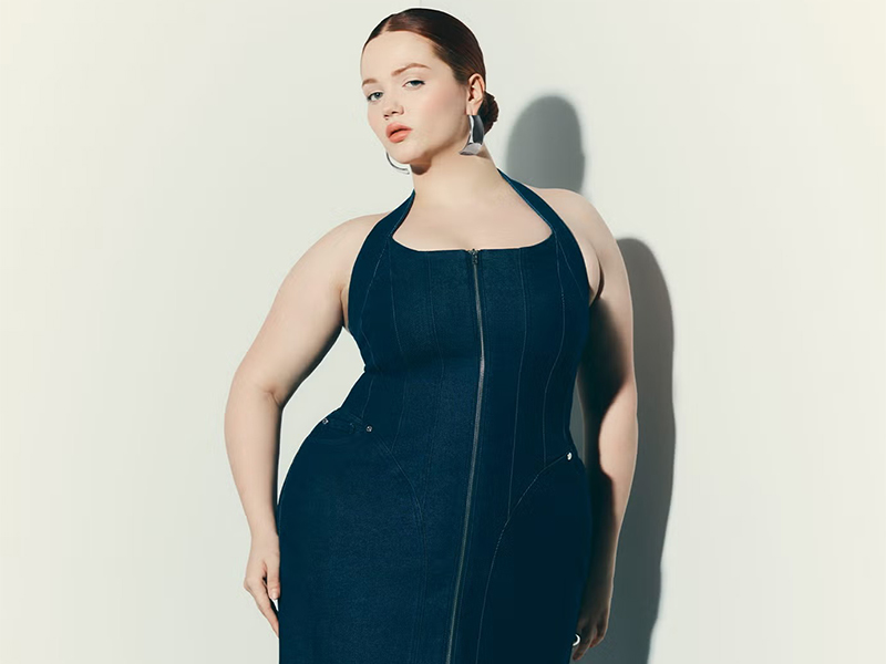 model wears denim corset dress from Eloquii while posing