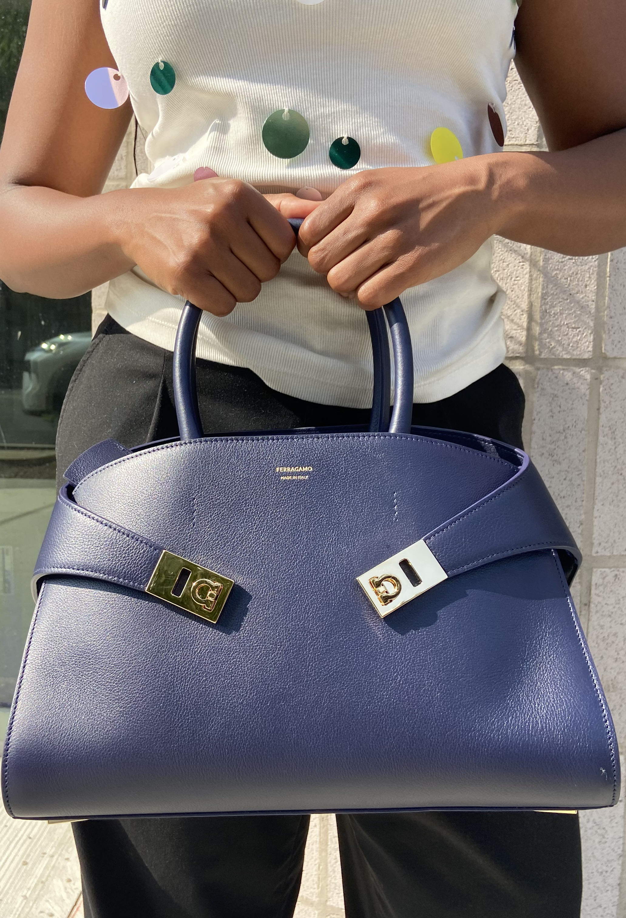 A woman holding a midnight blue handbag from Ferragamo
