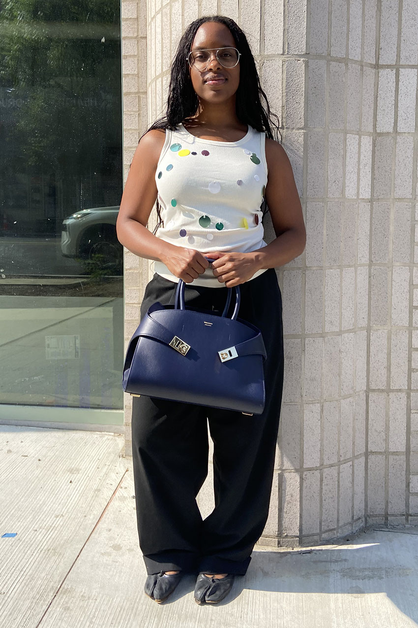 A woman holding a midnight blue handbag from Ferragamo