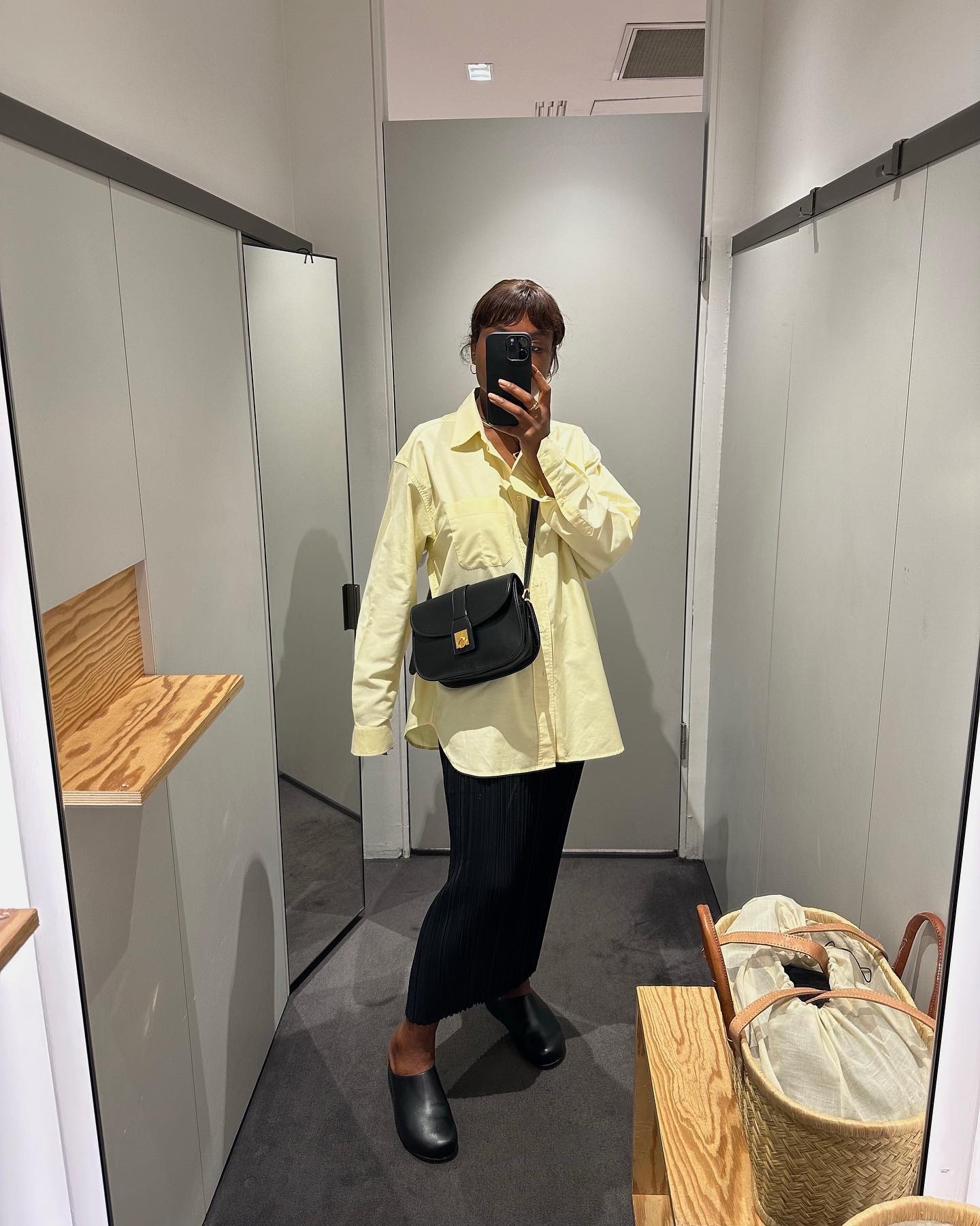 Parisian influencer Frann Fyne wears a black maxi skirt, a yellow button down, and black leather clogs.