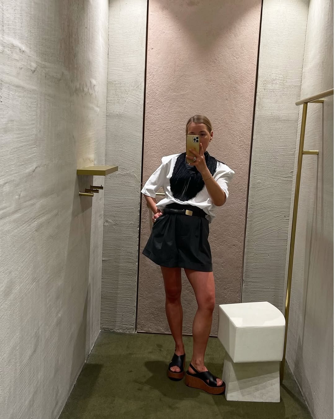 Influencer Anna wears Bermuda shorts, a white top and platform clogs.