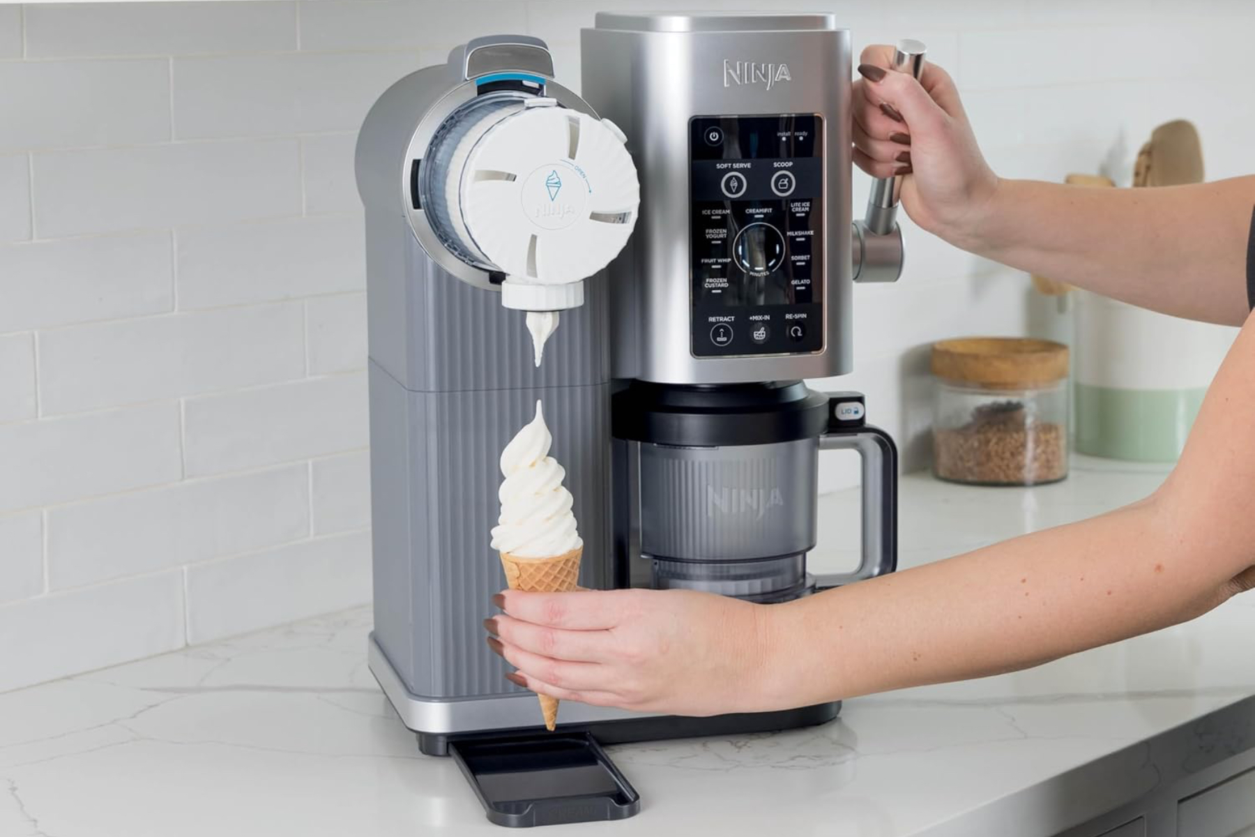 Ninja's Swirl soft serve dessert maker on top a counter dispensing vanilla ice cream.