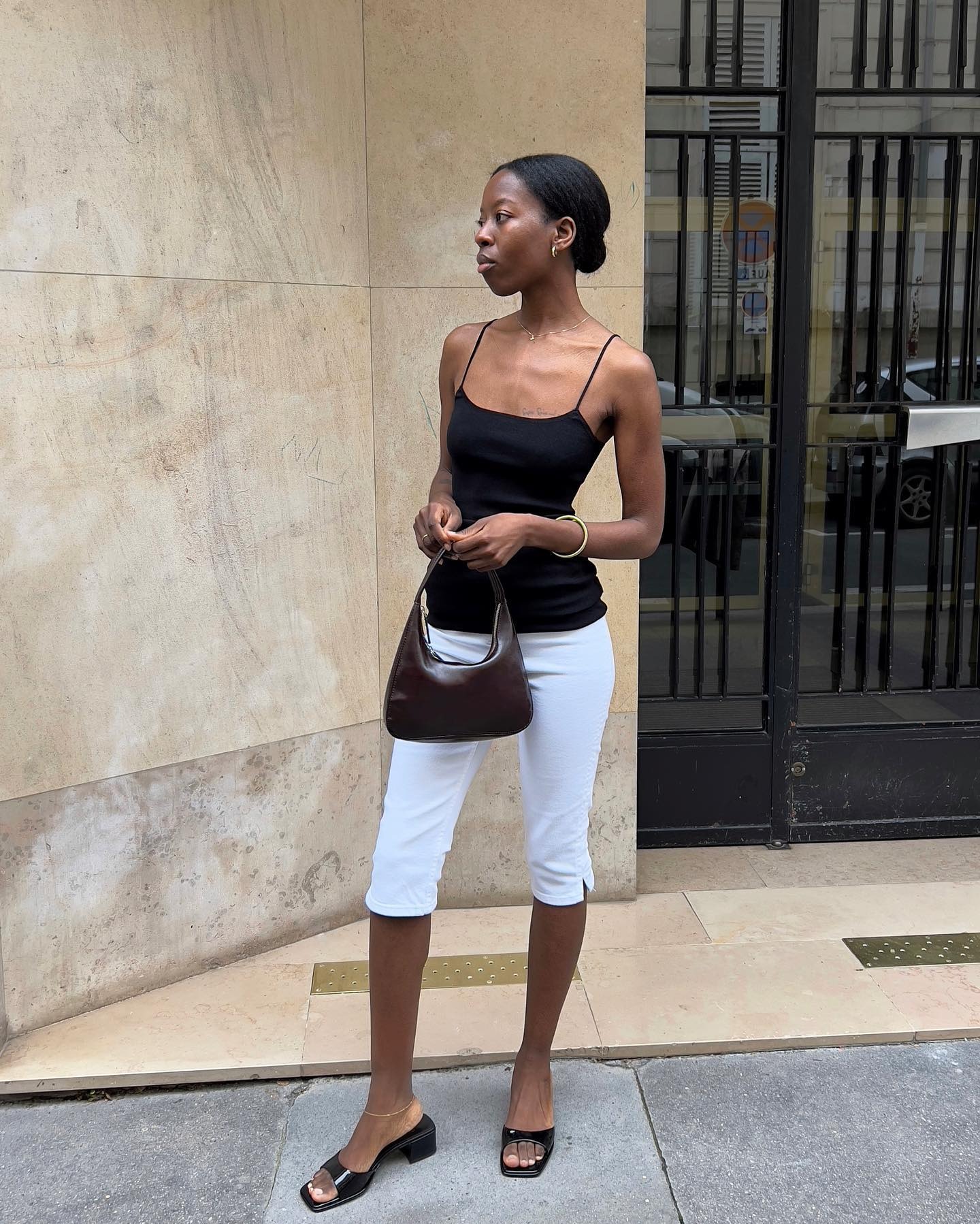 Influencer @sylviemus_ wears a black camisole top with white capri pants and black open-toe mules.